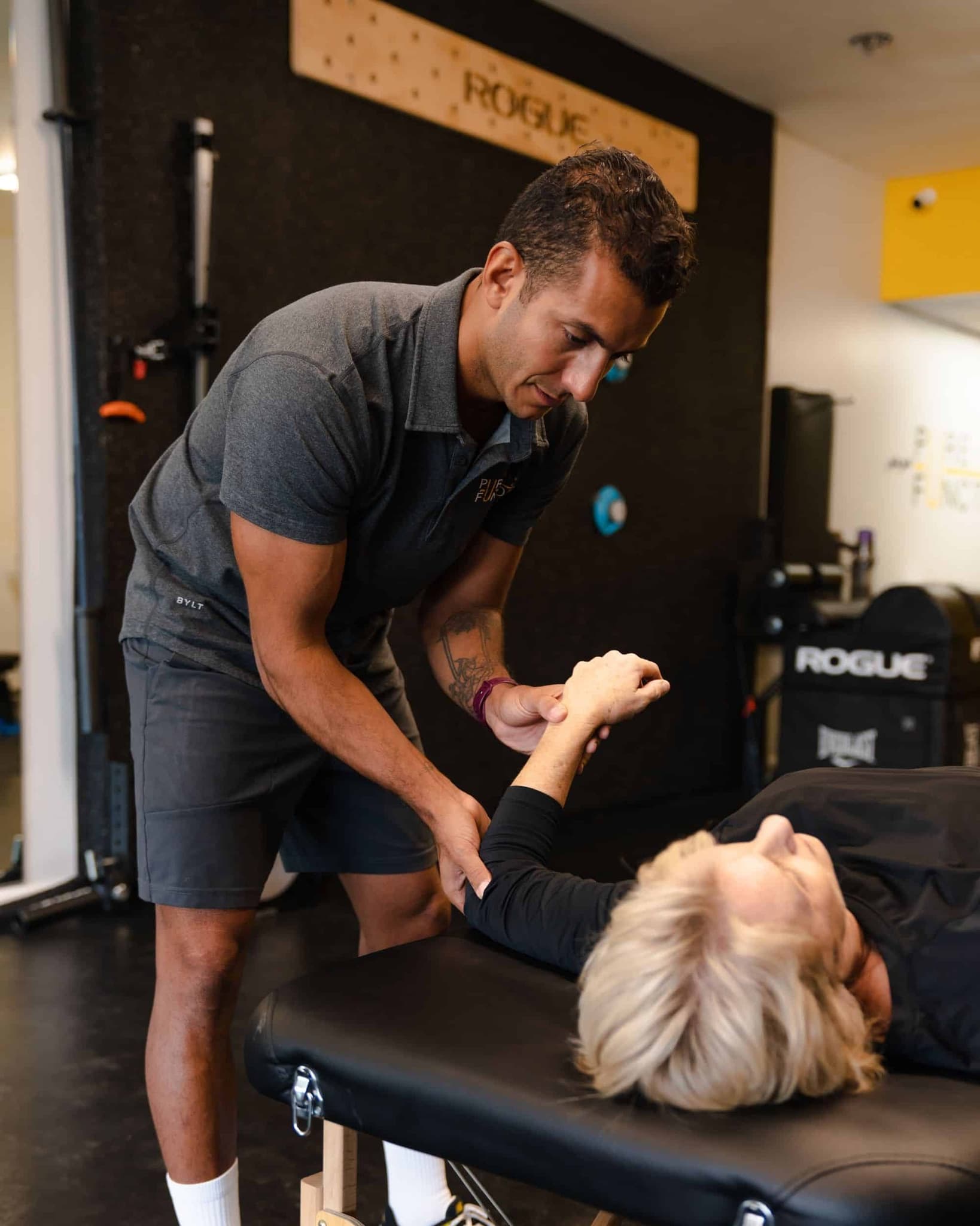 Coach measuring a client's overhead arm mobility on the assessment table