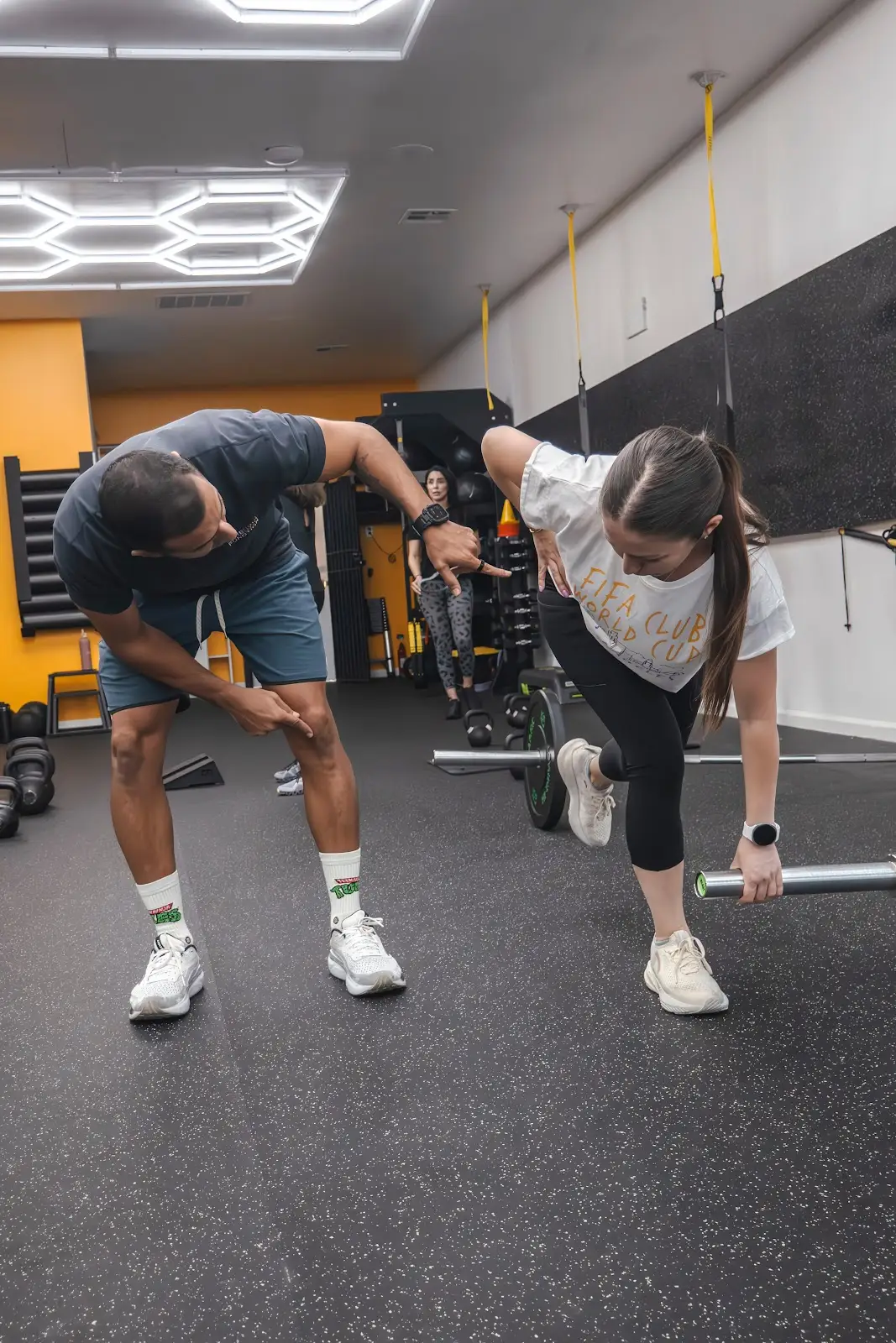 A coach cueing a client's hip position during a single-leg hinge