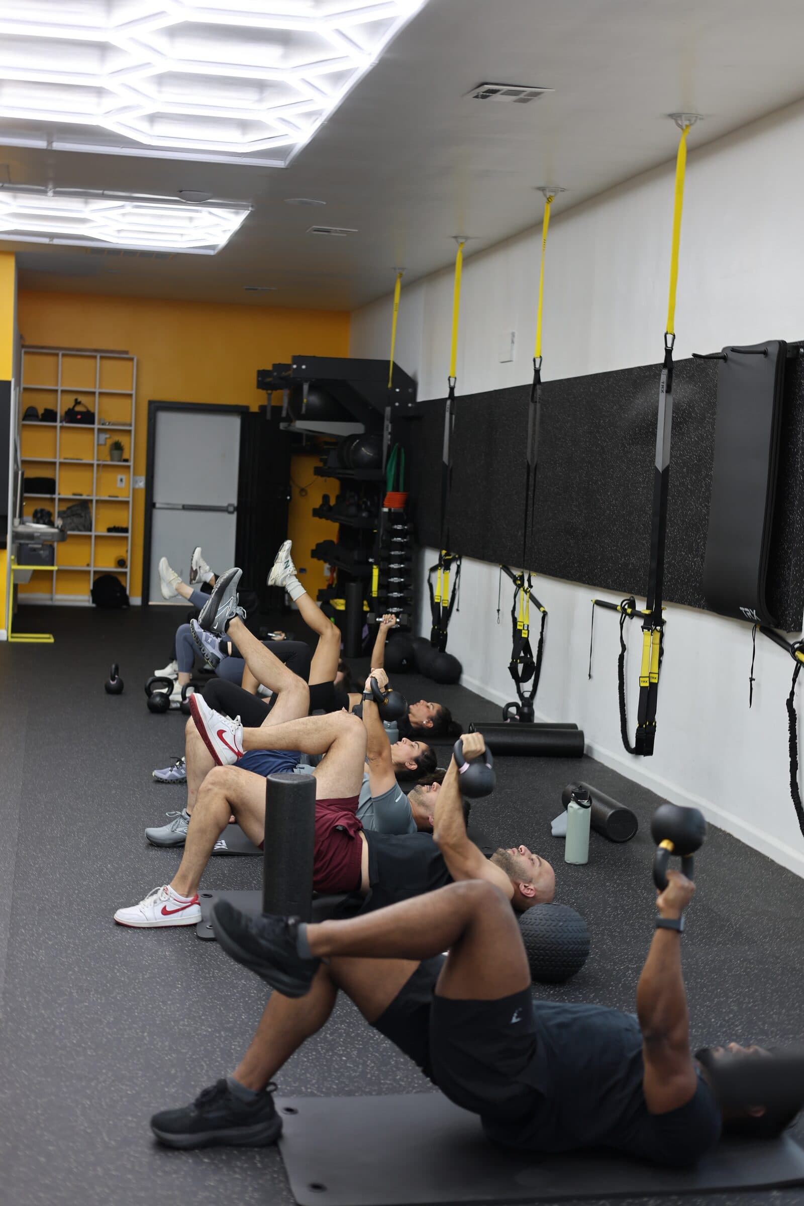 A group class performing single-leg hip lifts on the studio floor
