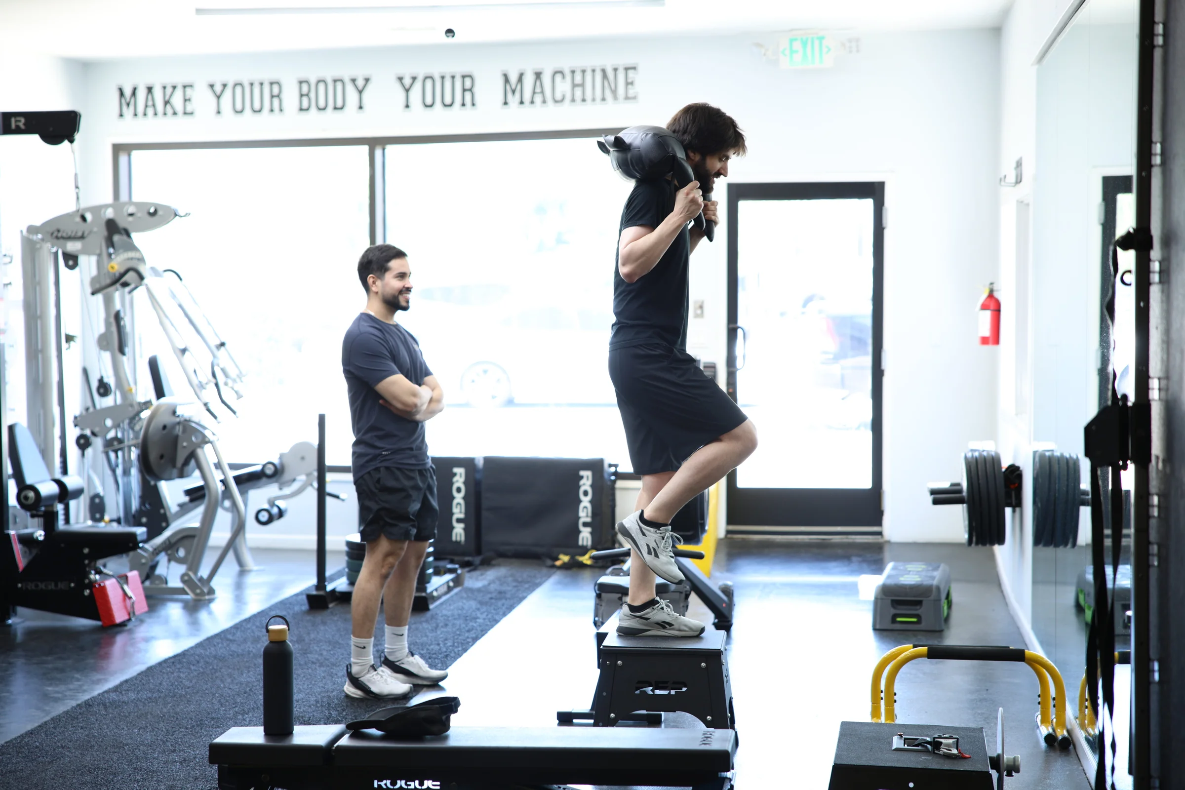 A coach watching a client perform a weighted step-up