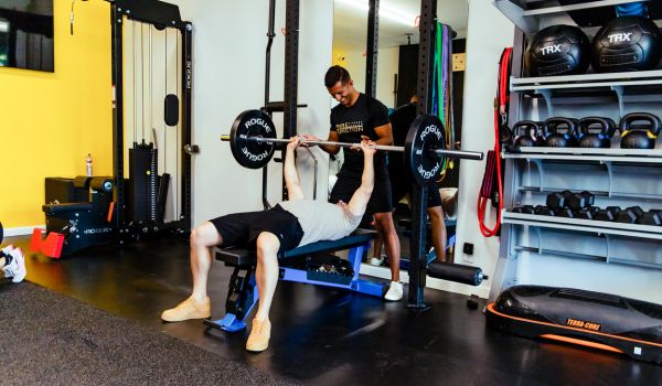 bench press for hypertrophy training being monitored by trainer